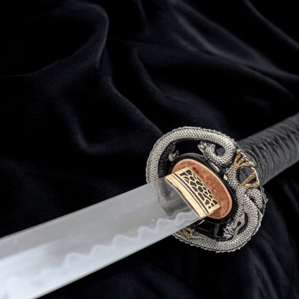 Kiryu katana close-up — T10 blade with hamon line, silver dragon tsuba, brass habaki, charcoal cotton ito